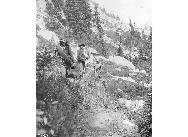 Three hikers on hillside with camping gear, vicinity of Mount Rainier, July 21, 1910 (SARVANT 79), illustrative activity photo
